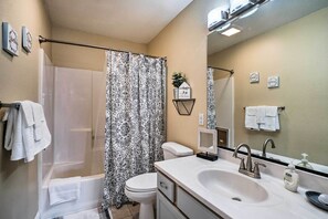A bathroom with a bathtub, toilet, and sink. There are towels hanging on the wall and a small plant on a shelf. - Stroll to Branson Strip: Condo on Golf Course (Branson)
