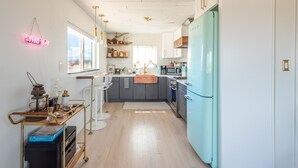 Une cuisine moderne avec un réfrigérateur de couleur turquoise, des armoires blanches et un plan de travail en bois.
