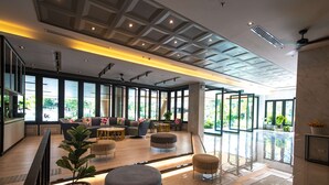 A spacious lobby with large windows, a seating area with sofas and ottomans, and a modern ceiling design. - Lewit Hotel Pattaya, a member of Radisson Individuals (Pattaya)