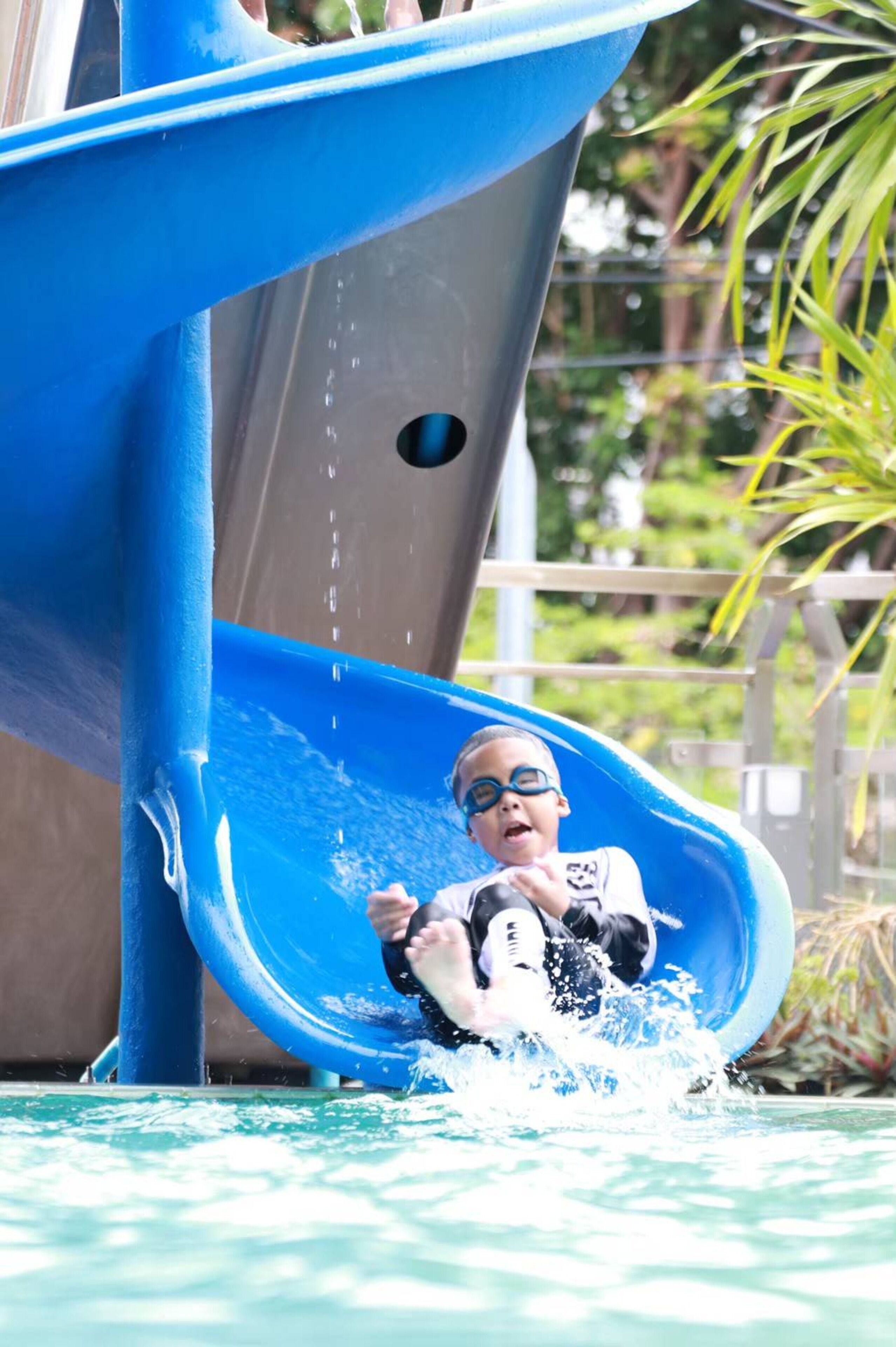 Un niño se desliza por un tobogán acuático azul en un parque acuático.