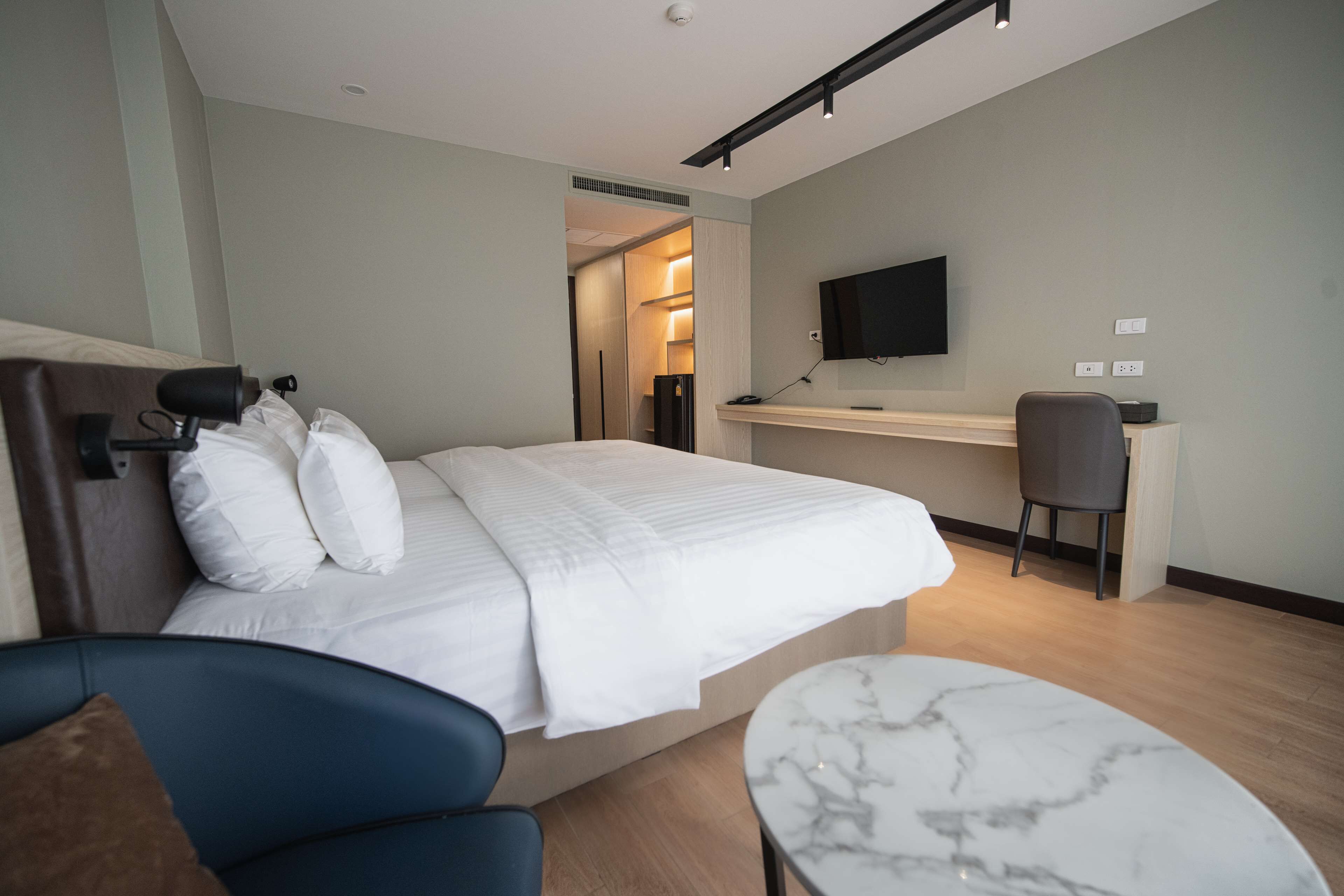 Una moderna camera d'albergo con un ampio letto, una scrivania, una TV e un angolo salotto.