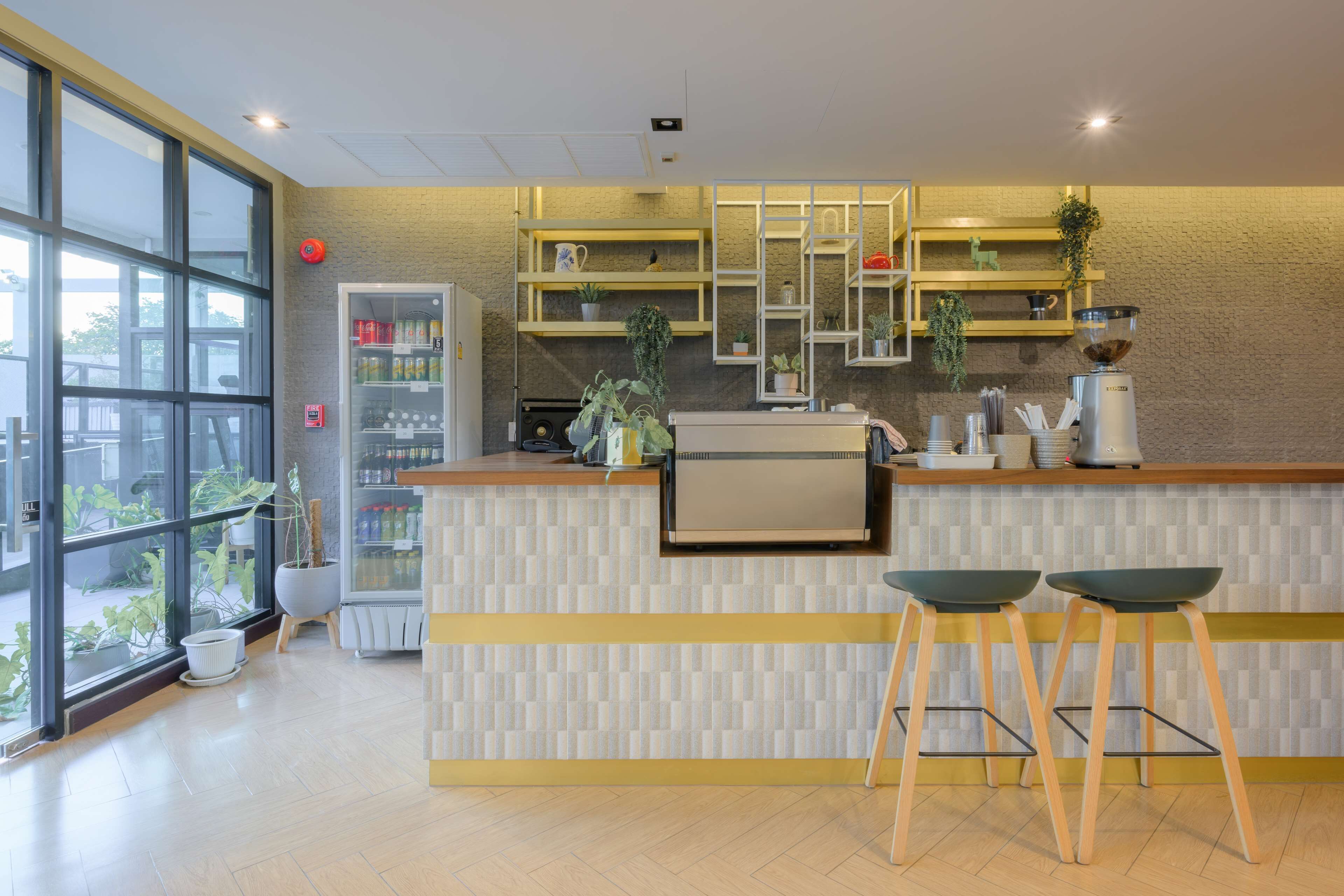 A modern kitchen with a bar area, wooden stools, and potted plants.