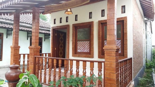A traditional building with a tiled roof, wooden columns, and a balcony with a wooden railing.