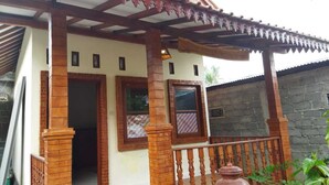 A house with a porch, wooden pillars, and a tiled roof.