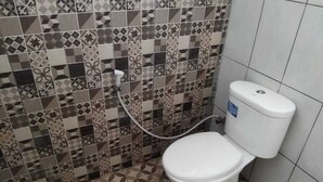 A bathroom with a toilet, a shower, and a tiled floor.
