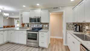 Una cucina moderna con mobili bianchi, un fornello in acciaio inossidabile e un forno a microonde.