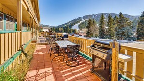 A patio with outdoor seating, a grill, and a view of snow-covered mountains. - Steps to Main St! Red River Condo w/ Mtn-View Deck (Red River)