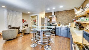 A modern kitchen with a central island, bar stools, and a dining table. - Steps to Main St! Red River Condo w/ Mtn-View Deck (Red River)