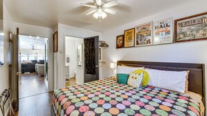 A bedroom with a large bed, a ceiling fan, and a view of a living area. - Steps to Main St! Red River Condo w/ Mtn-View Deck (Red River)