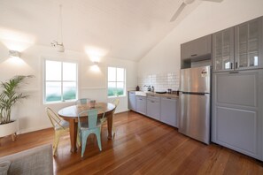 A modern kitchen with a large stainless steel refrigerator, wooden cabinets, and a dining area with a round table and chairs.