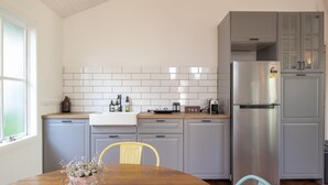 Eine moderne Küche mit grauen Schränken, einem Edelstahlkühlschrank und einem Holzespeisetisch mit Stühlen.