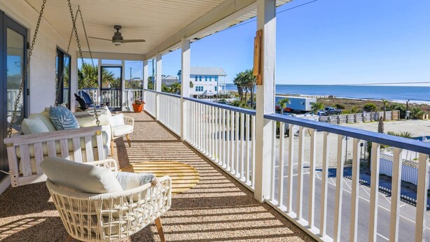 Un balcone coperto con sedie in vimini e vista sulla spiaggia.
