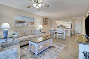 A living room with a sofa, coffee table, and a dining area with chairs and a table.