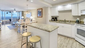 Una cocina moderna con armarios blancos, encimeras de granito y una zona de bar con taburetes.