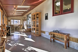 A spacious room with a wooden cabinet, a bench, and a dining area with chairs and a table.