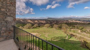 Un bâtiment en pierre doté d’un balcon donnant sur un paysage montagneux.