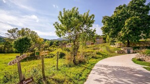 Ein Feldweg führt zu einem Steinhaus, an dem ein Wegweiser die Richtung nach 'CAROT' und 'Belfia' anzeigt.