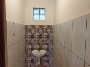 A small bathroom with a tiled wall, a window, and a sink.