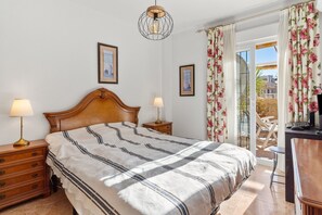 Une chambre à coucher avec un lit, deux tables de chevet avec des lampes, une tête de lit en bois et deux tableaux encadrés accrochés au mur.