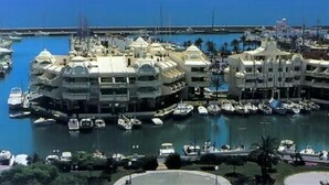 A marina with multiple boats docked, surrounded by multi-story buildings with balconies. - Family-Friendly Apartment with Private Terrace, Shared Pool, A/C & Wi-Fi (Benalmádena)