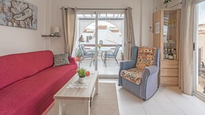A living room with a red sofa, a blue armchair, a wooden coffee table, and a view of the outside. - Penthouse Apartment Near the Beach with Sea View, Pool, Wi-Fi, A/C & Terrace (Torrevieja)