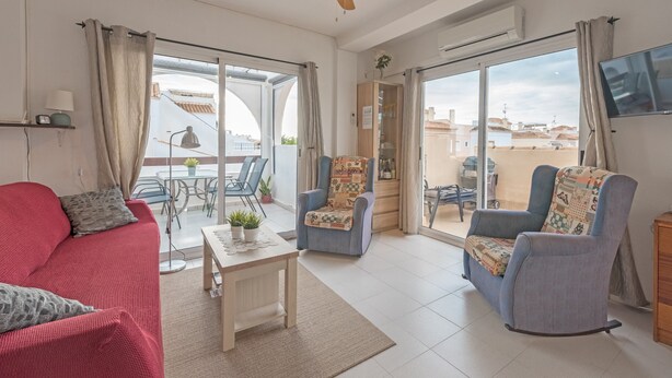 A living room with a red sofa, a blue armchair, a wooden coffee table, and a ceiling fan. - Penthouse Apartment Near the Beach with Sea View, Pool, Wi-Fi, A/C & Terrace (Torrevieja)