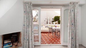 A room with a fireplace, a dining area with a table and chairs, and a view of a balcony with a tiled floor. - Bright and Spacious Apartment near Beach with Shared Pool, A/C & Wi-Fi (Nerja)