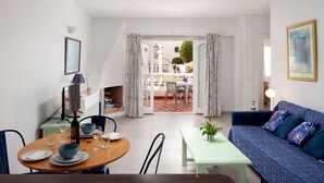 A dining area with a table set for two, a sofa, and a small table with a plant. - Bright and Spacious Apartment near Beach with Shared Pool, A/C & Wi-Fi (Nerja)