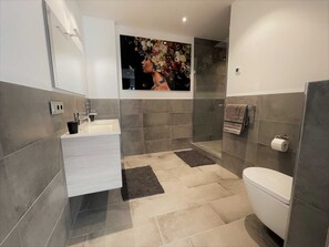 A modern bathroom with a shower, toilet, and sink. - Light-Filled Designer Apartment in Gütersloh - 90 m² - Flooded with Light (Gütersloh)