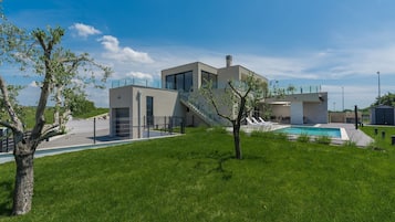 Una casa moderna con piscina, una scala e un cortile recintato.