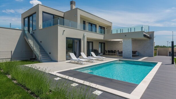 Une maison moderne à deux étages, dotée d’une piscine, d’un espace de détente extérieur et d’un escalier menant à l’étage supérieur.