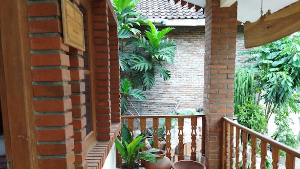 Un balcón de ladrillo con plantas en macetas y barandilla de madera.