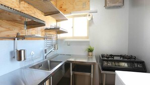 Una cocina compacta con electrodomésticos de acero inoxidable, una ventana y una pequeña planta en maceta.
