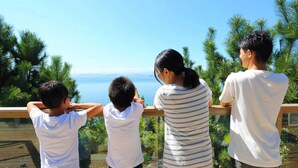 Una familia de cuatro personas en un balcón con vistas panorámicas a árboles y una masa de agua.