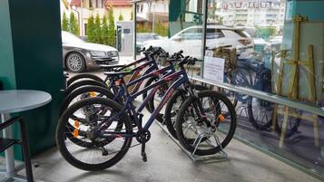 A bicycle rental station with multiple bikes and a sign indicating rental prices.