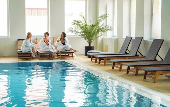 A pool area with lounge chairs and a potted plant. - Caprioara Spa&Wellness Resort (Covasna)