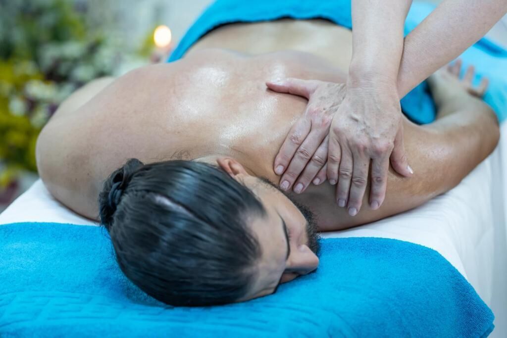 A person receiving a massage on a massage table with a blue towel.