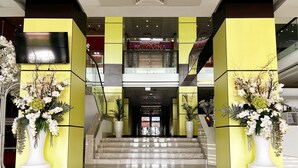 A modern lobby with a staircase, yellow walls, and large white vases with flowers. - Caprioara Spa&Wellness Resort (Covasna)
