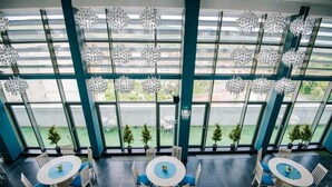 A modern hotel room with large windows, multiple dining tables, and decorative hanging lights. - Caprioara Spa&Wellness Resort (Covasna)