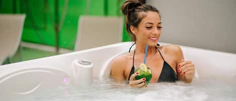 A person in a hot tub with a drink, surrounded by a green-tinted environment.