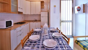 Cocina compacta con armarios blancos, microondas y una mesa de comedor para cuatro.