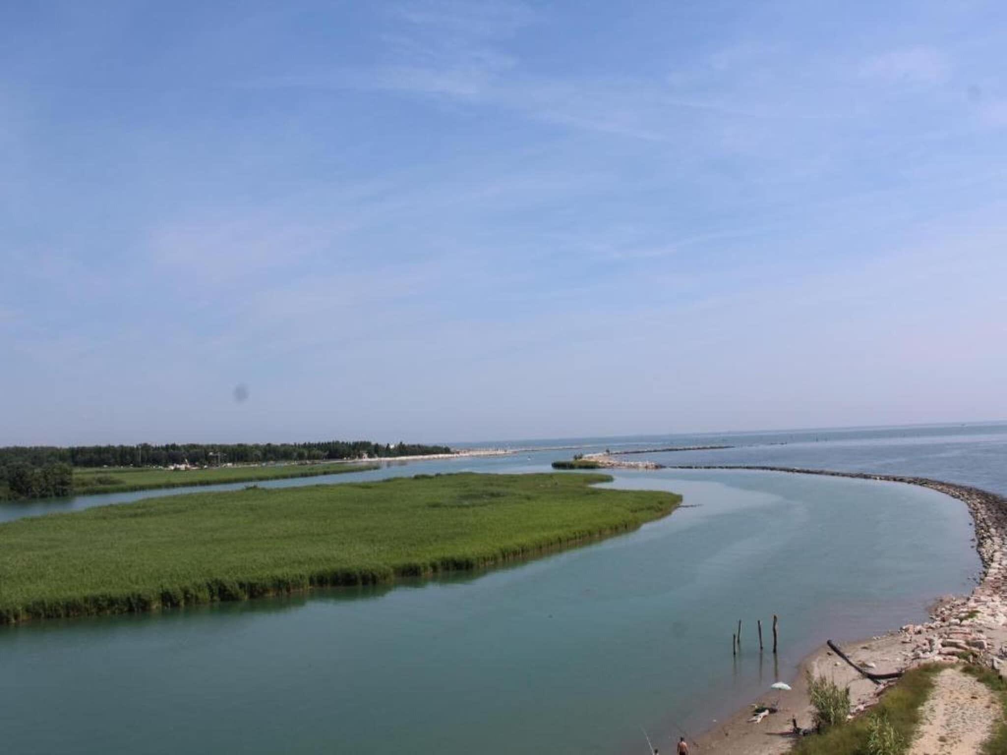 Ein Fluss mit Sandstrand und saftigen Wiesen.
