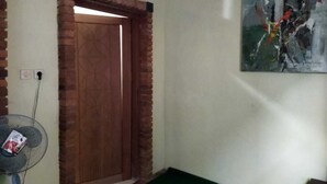Ein Zimmer mit Holztür, einem Ventilator und einem Bild an der Wand.