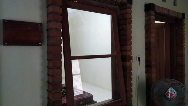 Ein Fenster mit Ziegelrahmen, ein Wandventilator und eine Tür mit einer Ziegelbogenöffnung.