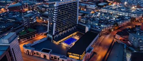 A high-rise hotel with a prominent 'Windsor' sign, a rooftop pool, and a parking lot.