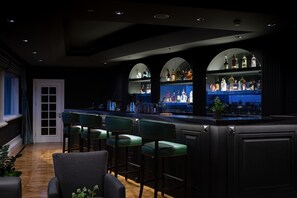 A bar area with a counter, bar stools, and shelves of liquor bottles. - Windsor Hotel & Convention Center (Istanbul)