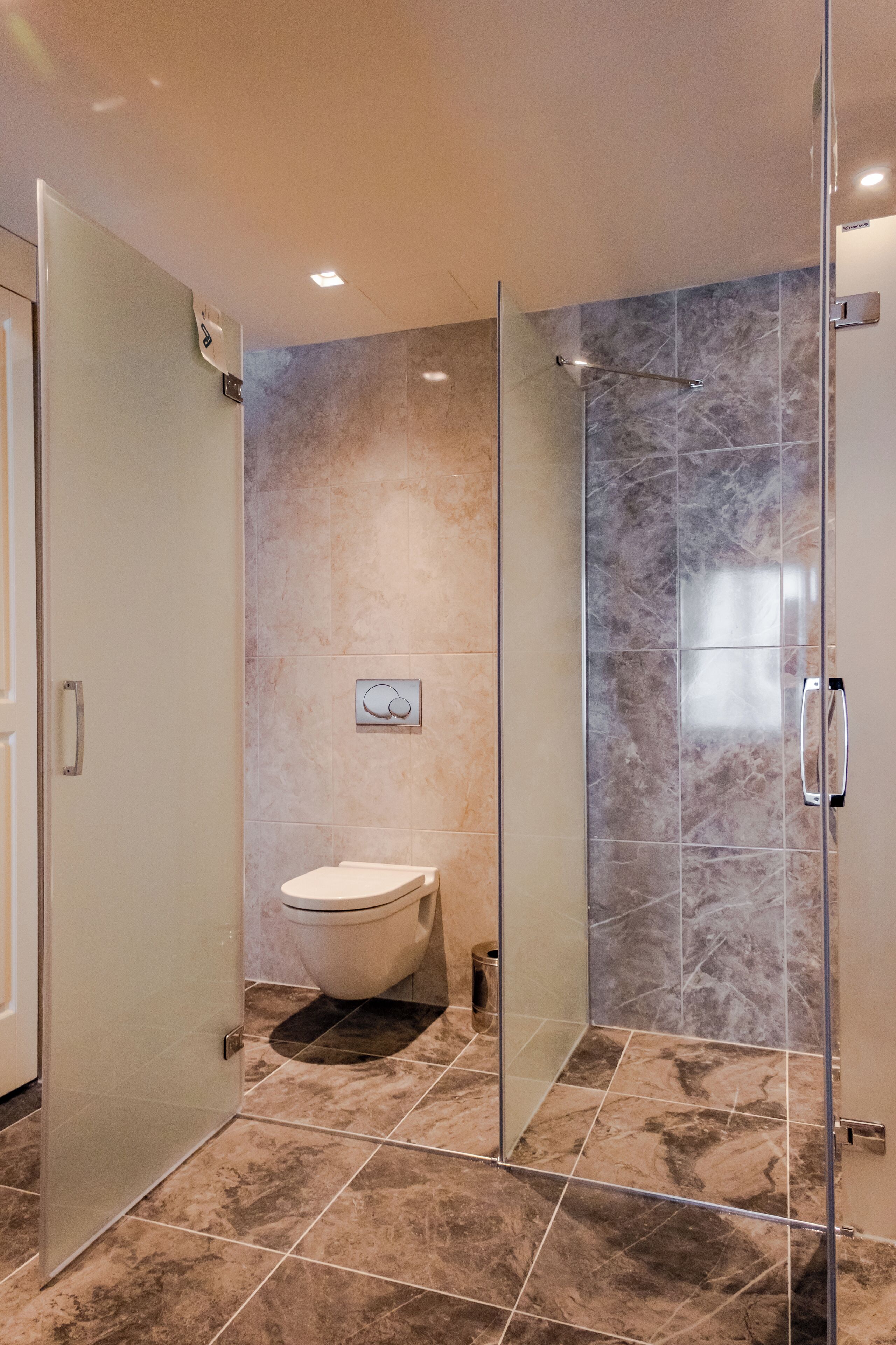 Ein modernes Badezimmer mit einer Duschkabine, einer Toilette und Marmorfliesen.