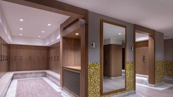 A modern bathroom with wooden lockers, a large mirror, and a tiled floor.