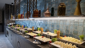 A buffet with various food items and decorative jars on the counter. - Windsor Hotel & Convention Center (Istanbul)