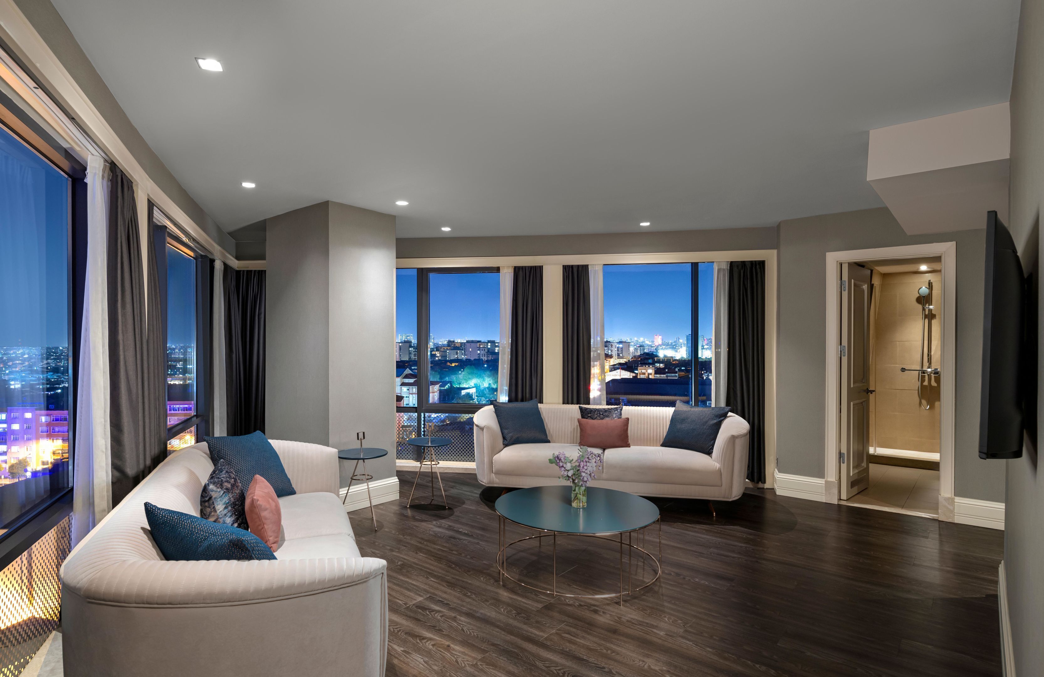 A modern living room with two sofas, a coffee table, and a city view through large windows.